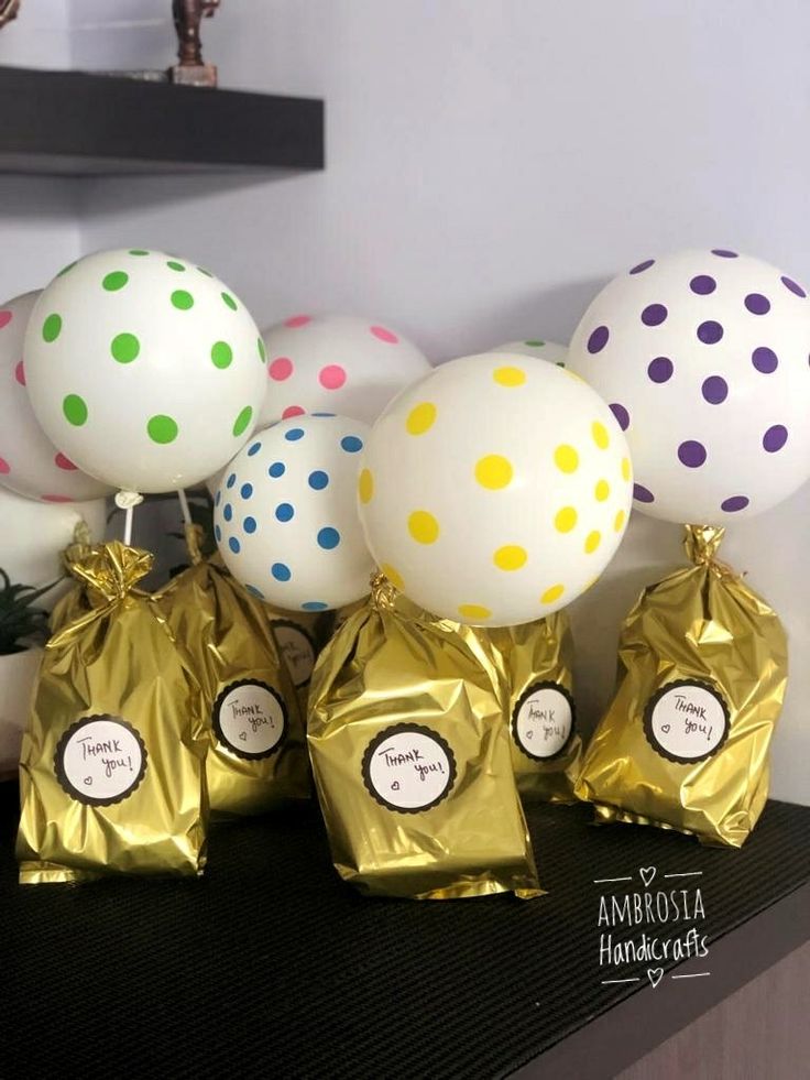 there are balloons and bags on the table with some gold foil wrapped around them,