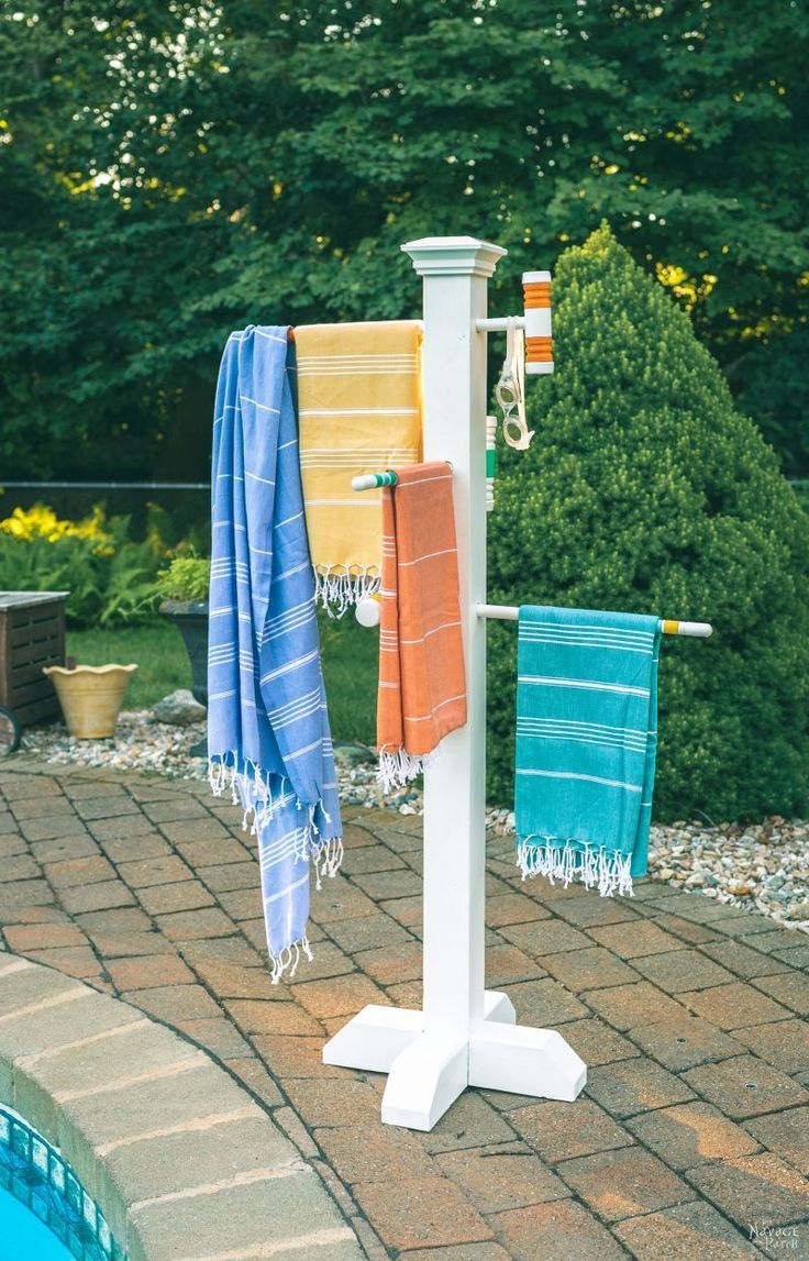 towels are hanging on a towel rack by the pool