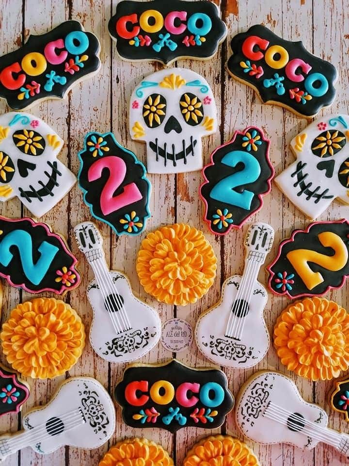 decorated sugar cookies arranged in the shape of guitars and skulls on a wooden table with decorations