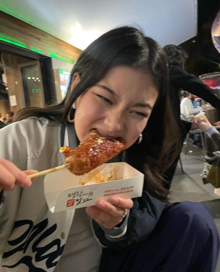 a woman eating food with chopsticks in her mouth