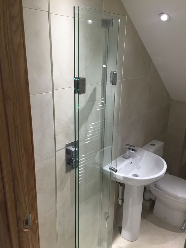 a bathroom with a toilet, sink and glass shower stall in the middle of it