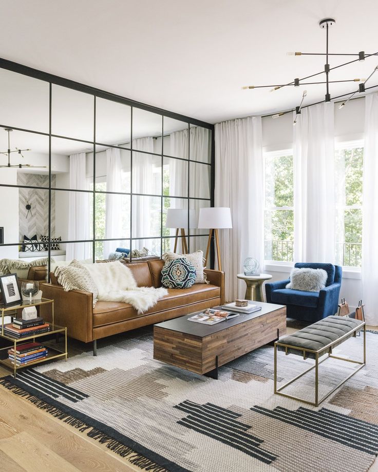 a living room filled with furniture and large mirrors on the wall above it's windows