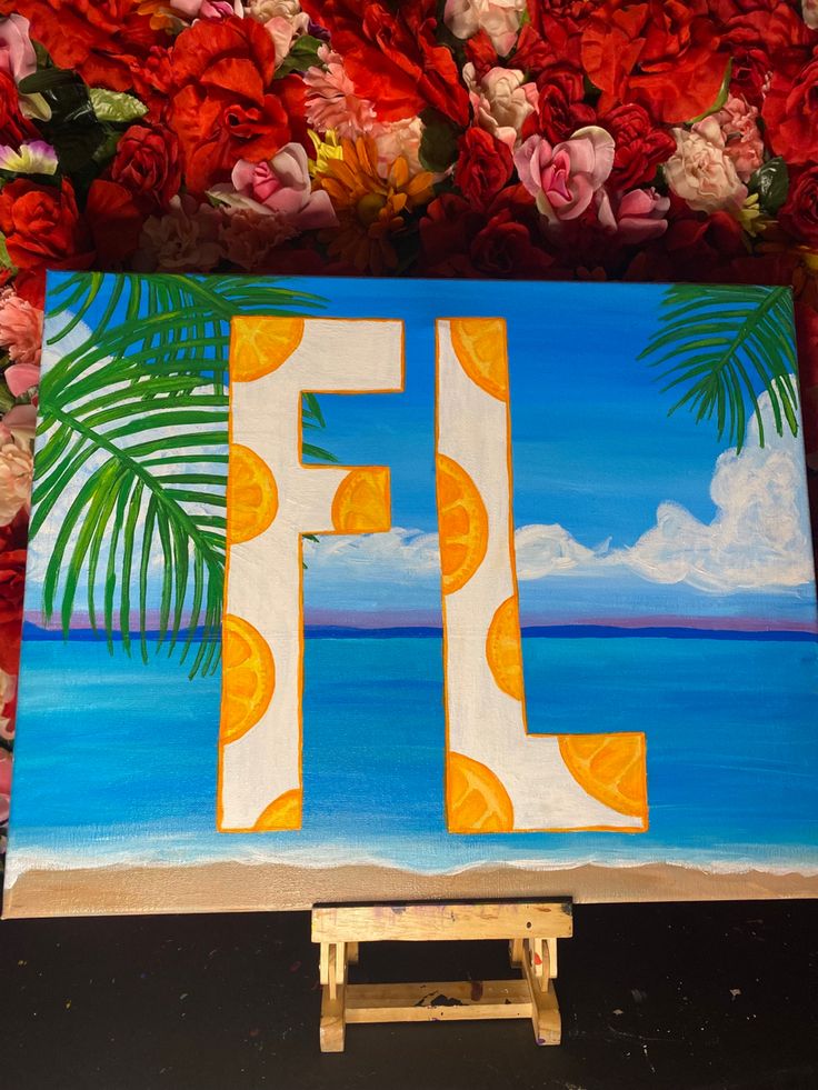 the letter f is painted on an easel in front of flowers