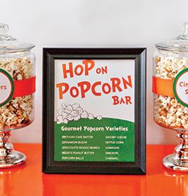 a glass jar filled with popcorn sitting next to a framed sign on top of a table