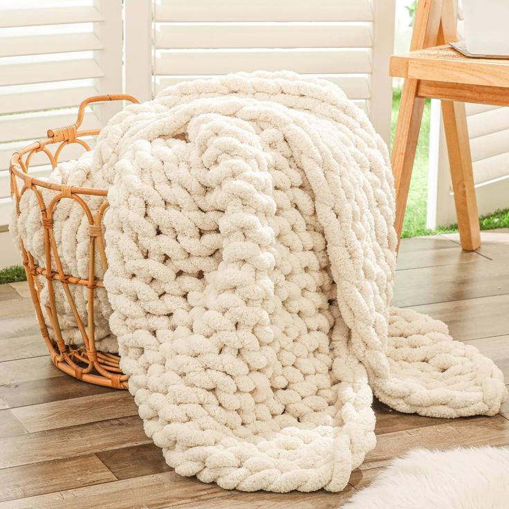 a white blanket sitting on top of a wooden floor next to a basket and chair