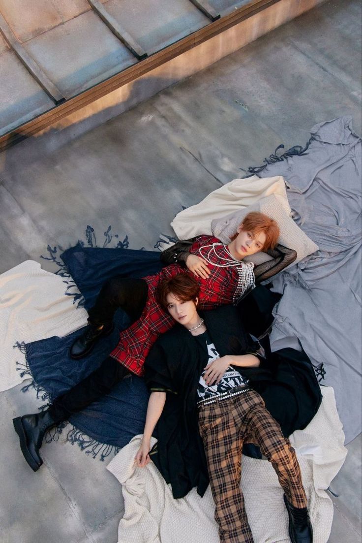 two young women laying on top of a bed