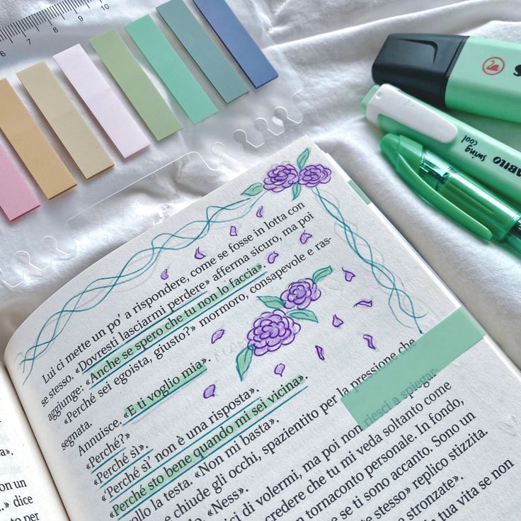 an open book with markers and pens on top of it next to other writing materials