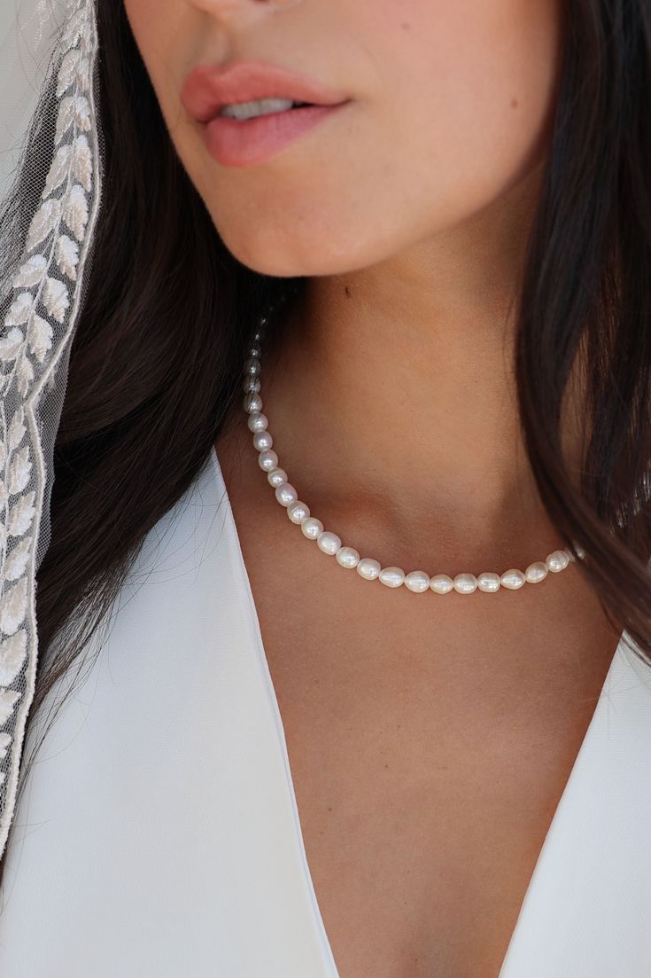 a woman wearing a necklace with pearls on it