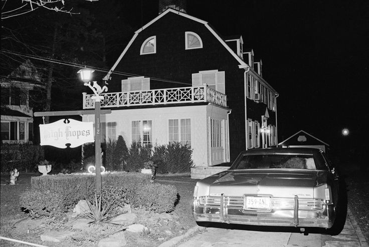 an old car parked in front of a house at night with street lights on the roof