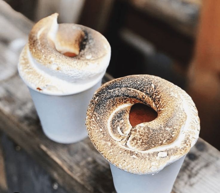 two cupcakes sitting on top of a wooden table covered in frosted icing