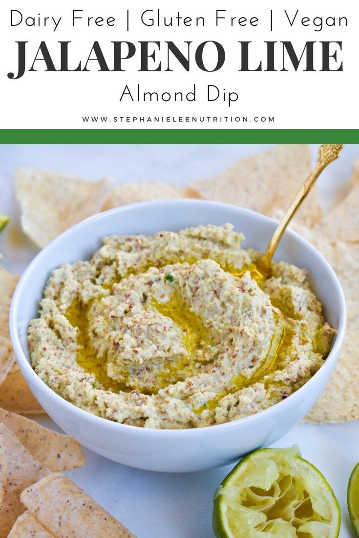 a white bowl filled with dip surrounded by tortilla chips and avocado