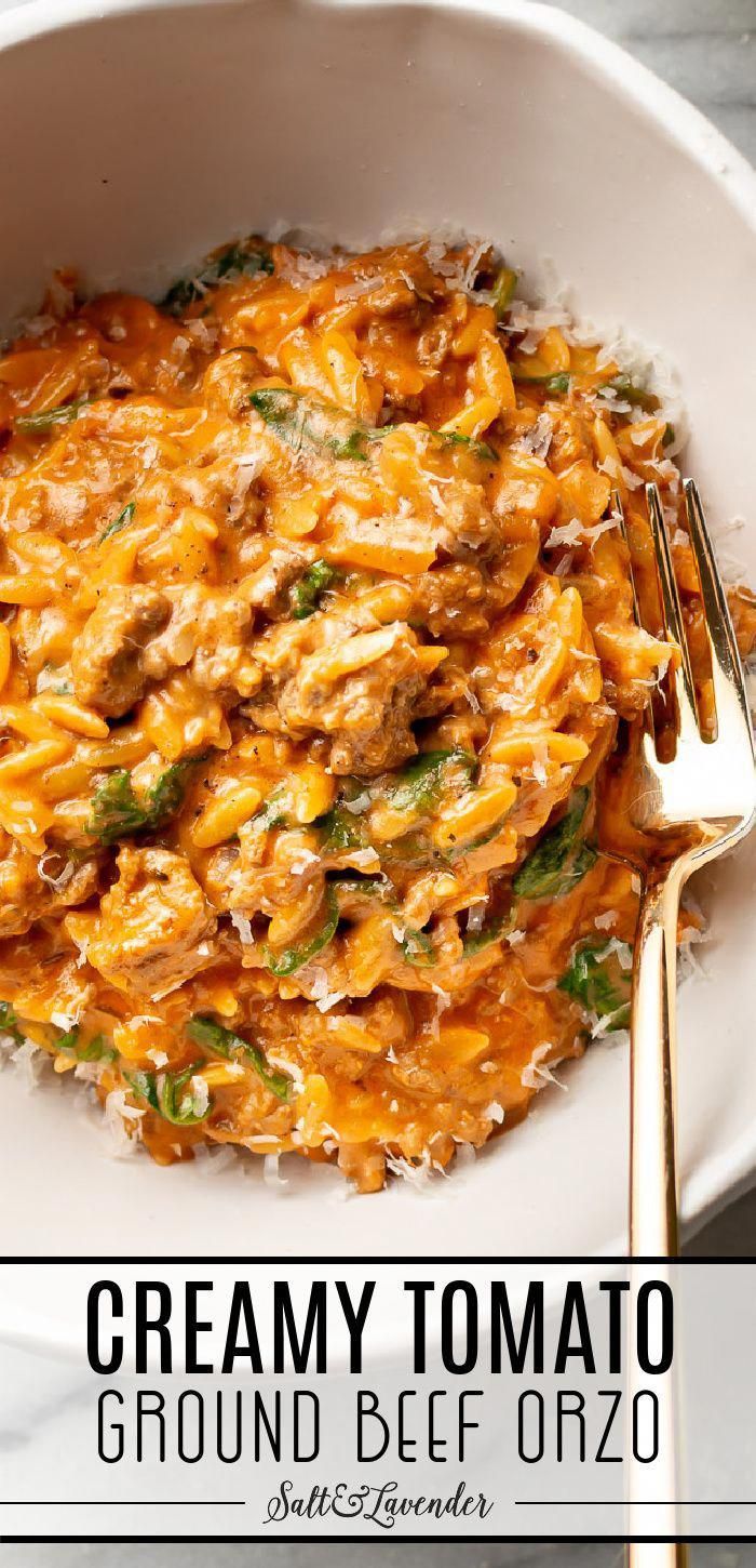 a white bowl filled with creamy tomato and cheese casserole next to a gold fork