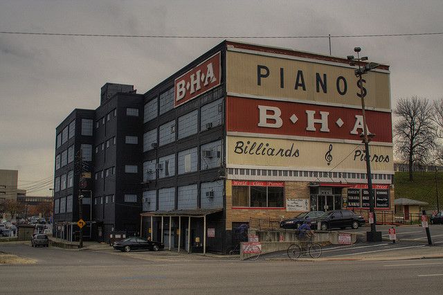 an old building with piano's b - ha sign on the side and cars parked in front