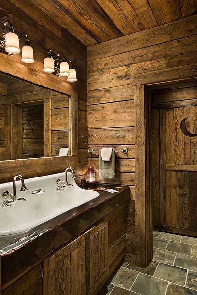 a rustic bathroom with wood paneling and stone flooring is pictured in this image