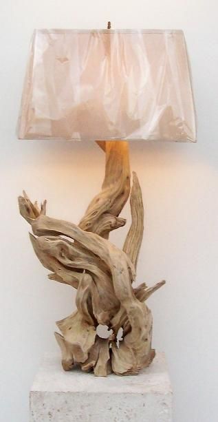 a lamp that is sitting on top of a white block with a piece of driftwood in front of it