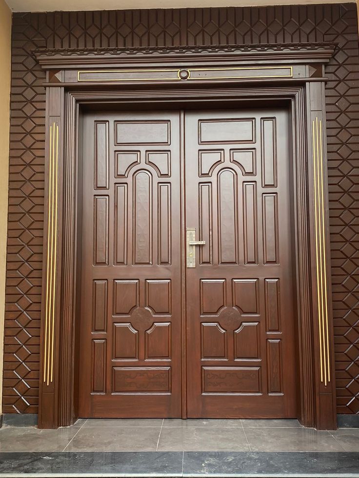 two wooden doors with decorative designs on the side of a building's front door