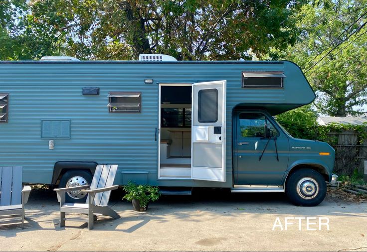 a blue trailer parked next to a picnic table with chairs around it and trees in the background