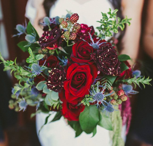 a bride holding a bouquet of red roses