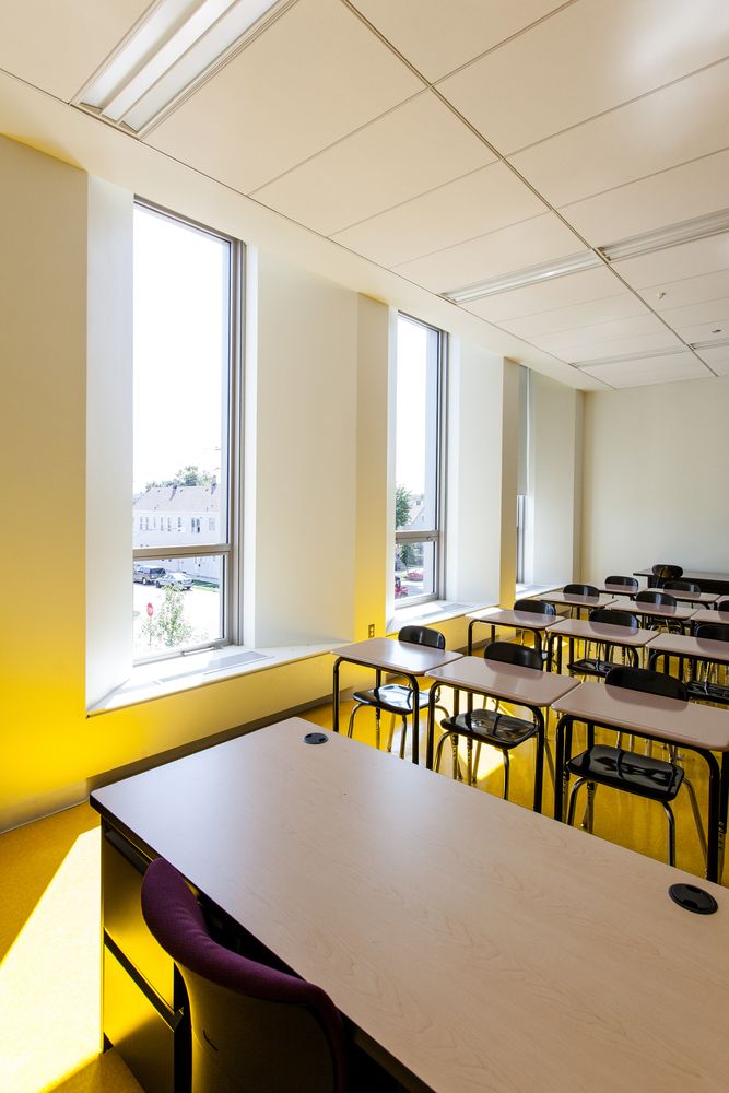 an empty classroom with desks and chairs in front of large windows on the wall