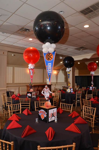 balloons and decorations are on the tables at a basketball themed party in a banquet hall