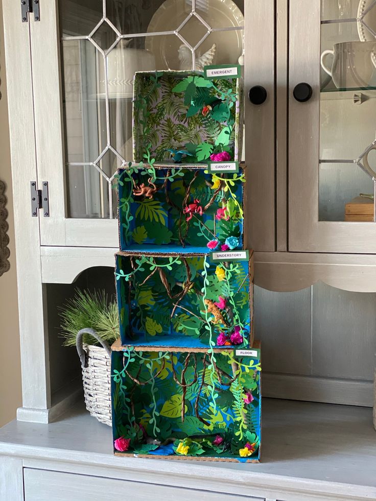 a set of three boxes sitting on top of a white dresser next to a glass cabinet