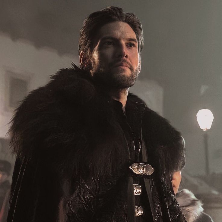 a man dressed in black and wearing a fur coat