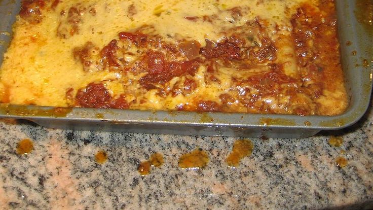 a casserole dish with meat and cheese in it on a granite counter top