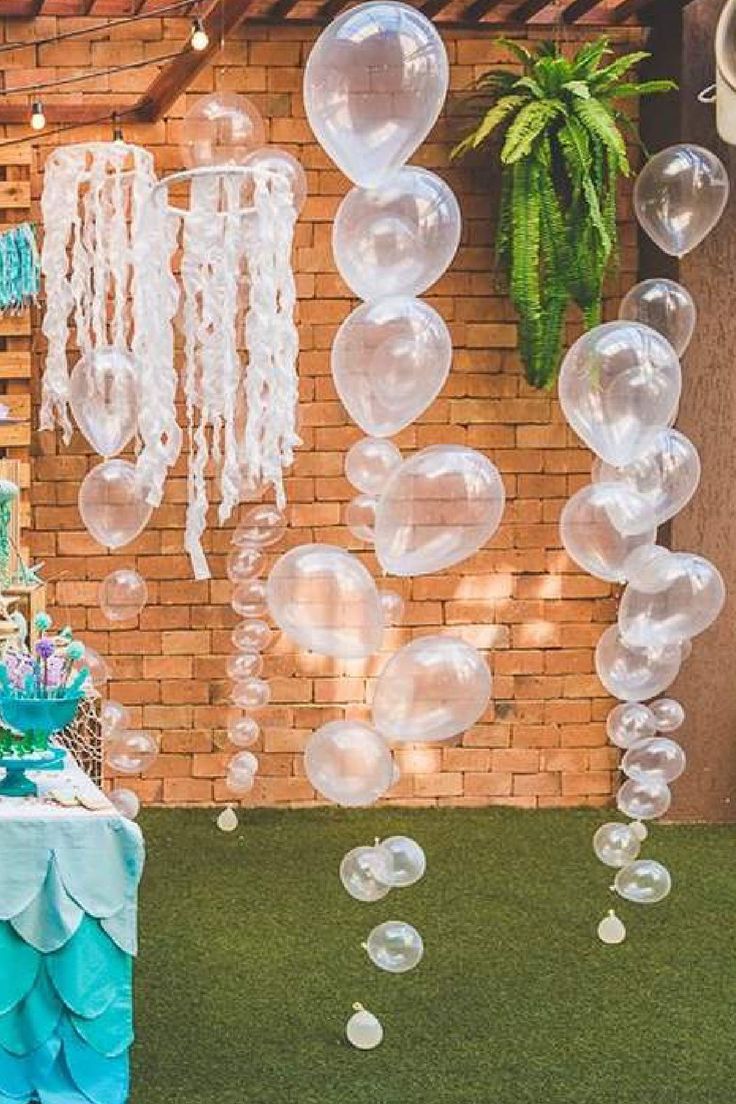 an outdoor party with balloons and streamers hanging from the side of a brick building