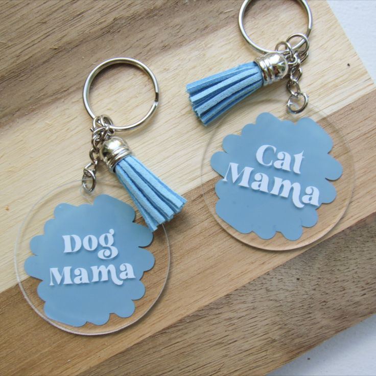 two acrylic keychains with tassels on them that say cat mama and dog mama