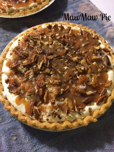 two pies sitting on top of a table covered in pecans and caramel