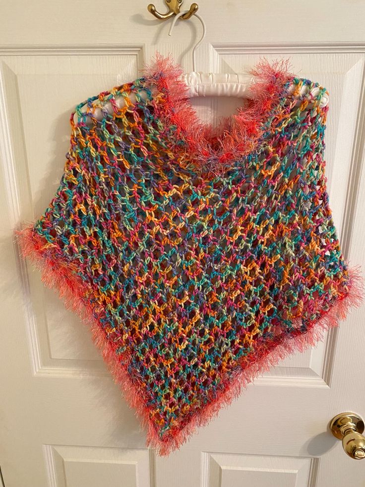 Add a touch of bohemian style to your little girl's outfit with this beautiful handmade poncho shawl. The pink and multi color and fringe accents give it a playful and fun look that is perfect for travel or casual occasions. The round neckline and pullover closure make it easy to wear and comfortable for all-day wear. Made with care in the United States, this sweater is a one-of-a-kind piece that your little girl will love. The crochet fabric type adds texture and interest to the garment, while the vintage style gives it a unique touch. It measure 25 inches wide and 22 inches in length. The head opening is 24 inches. Perfect for girls of all ages, this cape-style sweater is a must-have addition to any wardrobe. Spring Multicolor Tassel Shawl, Pink Bohemian Poncho For Spring, Multicolor Fringe Shawl For Spring, Spring Multicolor Fringe Shawl, Spring Bohemian Pink Poncho, Spring Multicolor Shawl With Fringe, One Size Bohemian Pink Poncho, Multicolor One-size Festival Poncho, One Size Multicolor Poncho For Festival