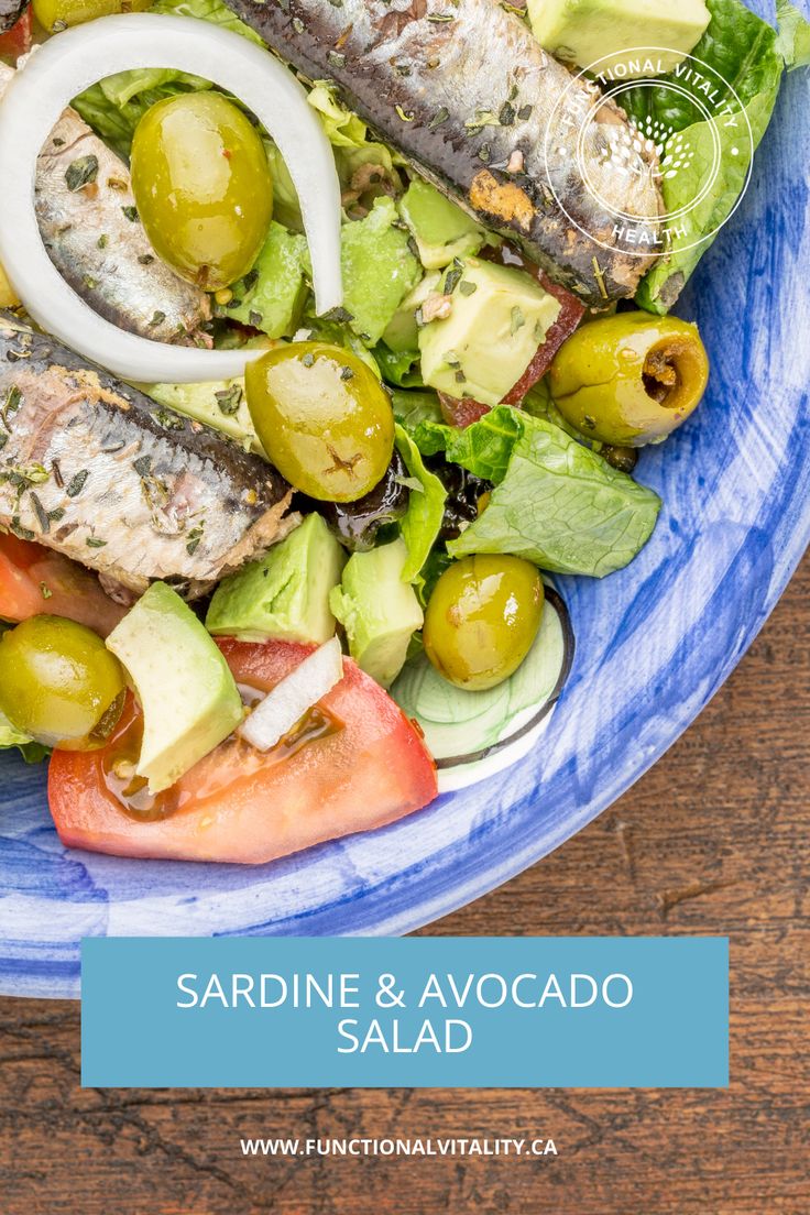 salad with fish, tomatoes, avocado and olives in a blue bowl