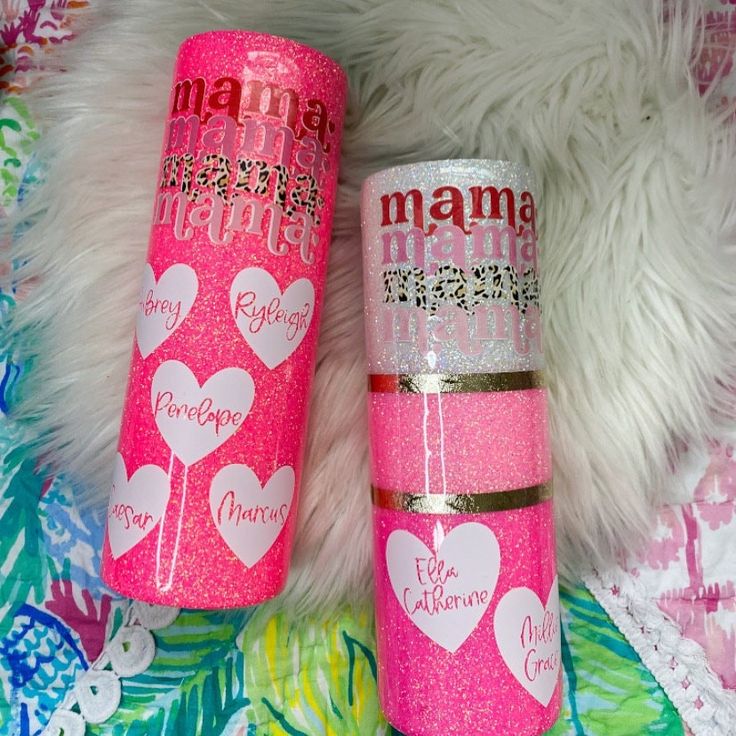 two personalized pink glitter tumbles with hearts on them sitting next to each other