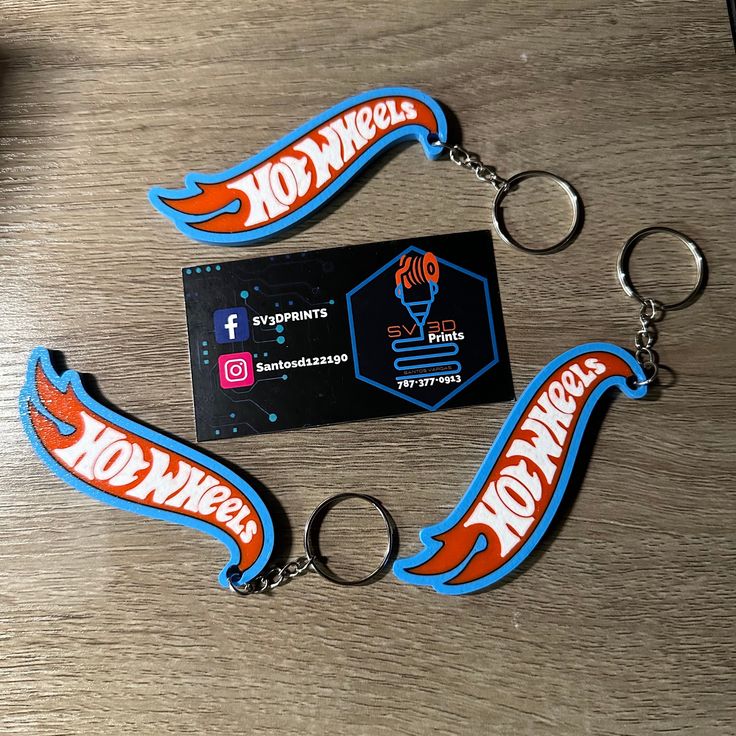 two keychains with the words hot wheels on them are sitting on a table