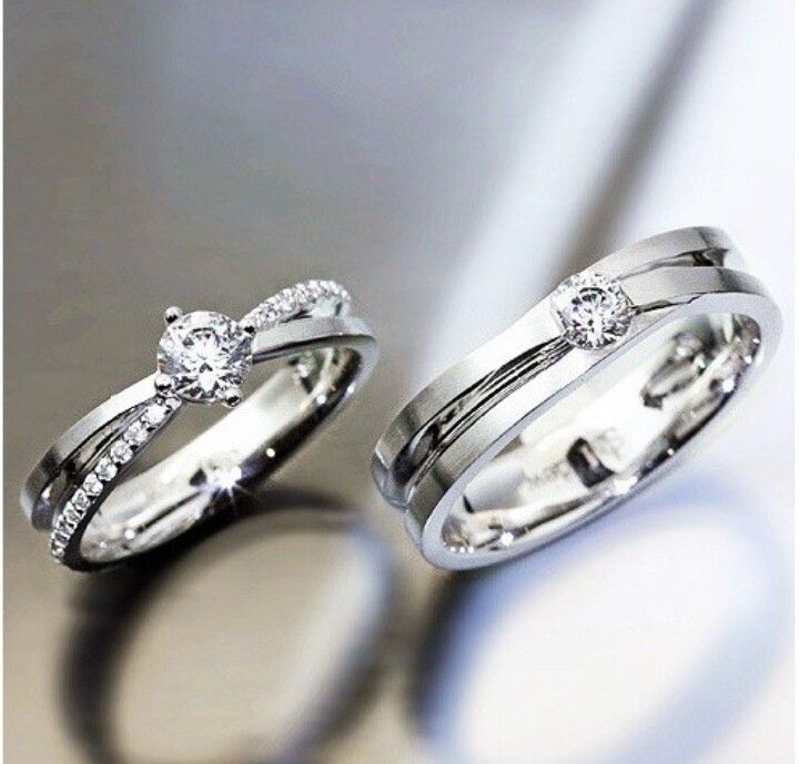 two wedding rings with diamonds on them sitting next to each other