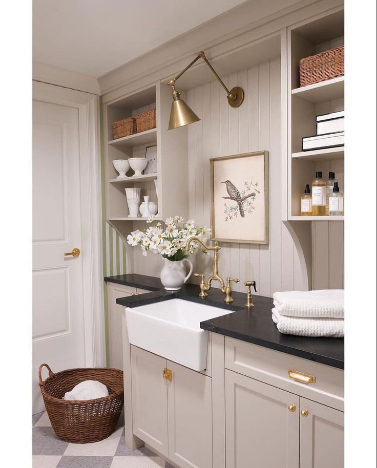 a white kitchen with black counter tops and gold faucets on the wall above it