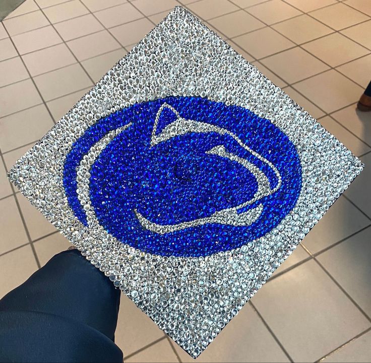 a blue and silver graduation cap with the penn logo on it is being held by someone's hand