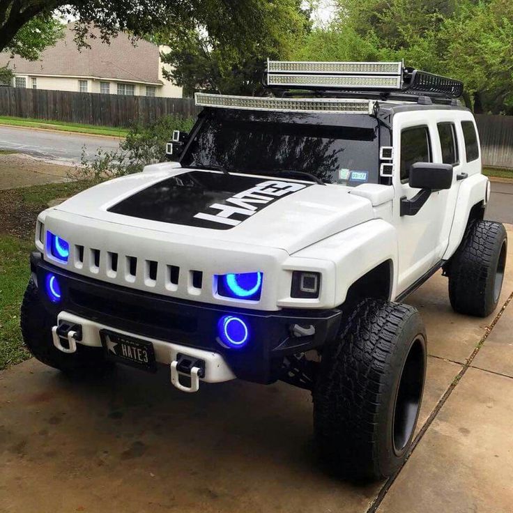 a white hummer truck with blue leds on the front and side lights is parked in a driveway