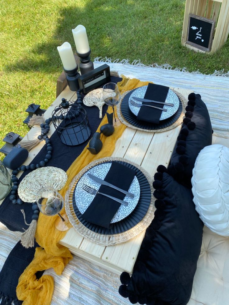 a table with black and white plates on it in the middle of a yard area