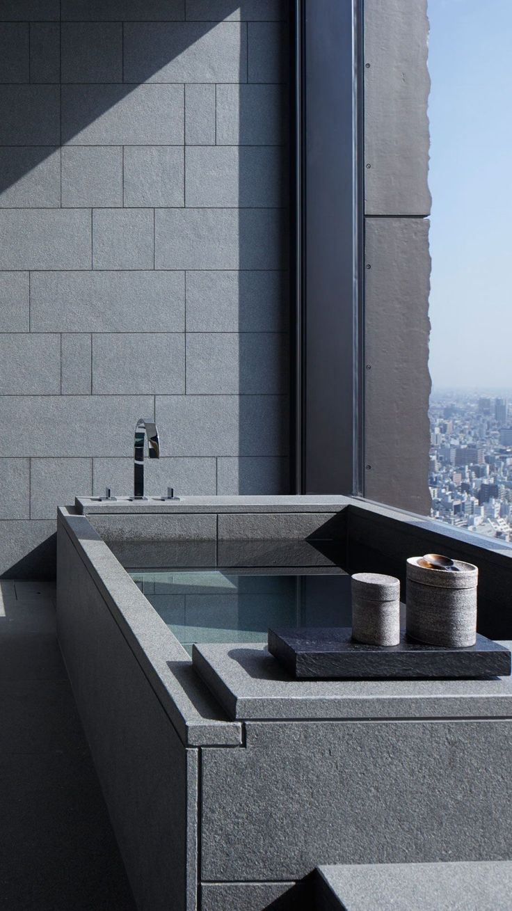 a bath tub sitting next to a window with a view of the city in the background