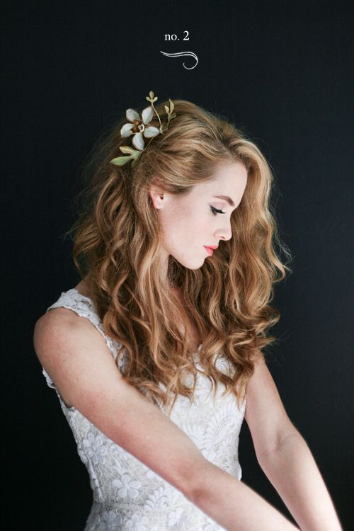 a woman with long red hair wearing a flower in her hair is looking down at the camera