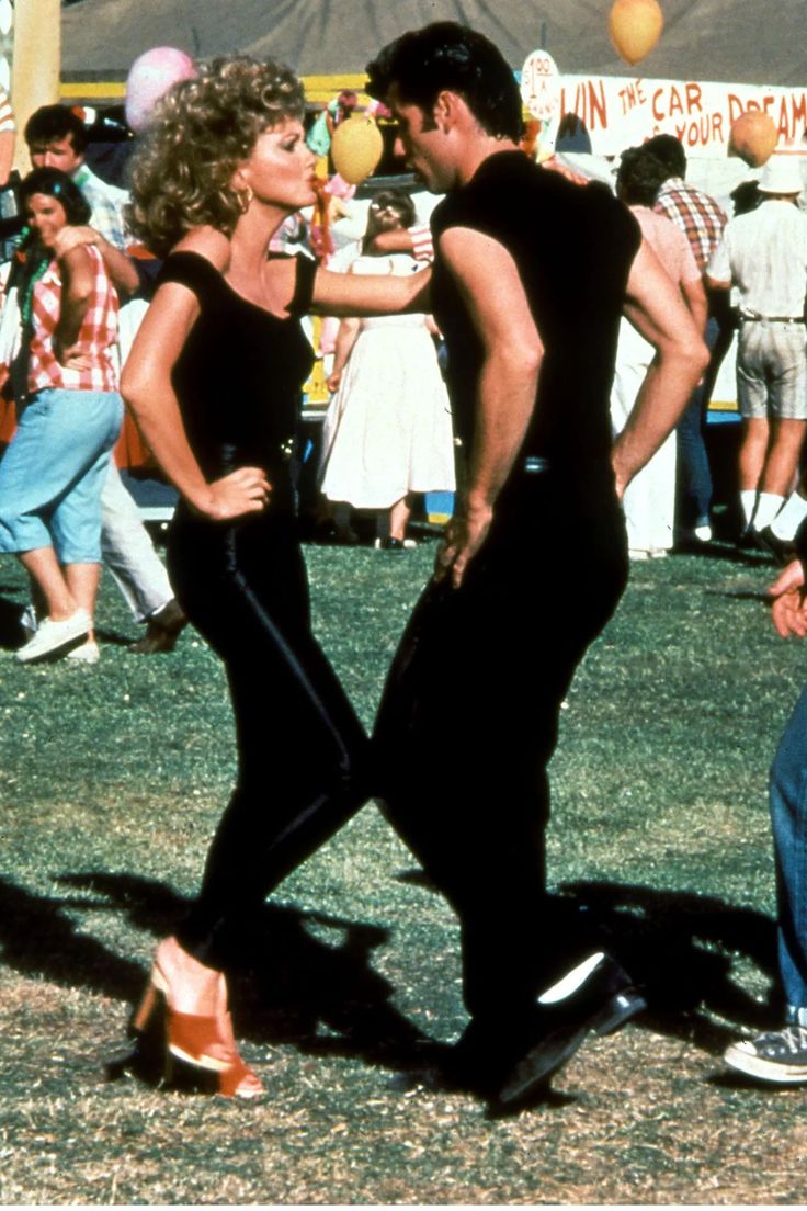 a man and woman dancing in front of a crowd at an outdoor event with balloons