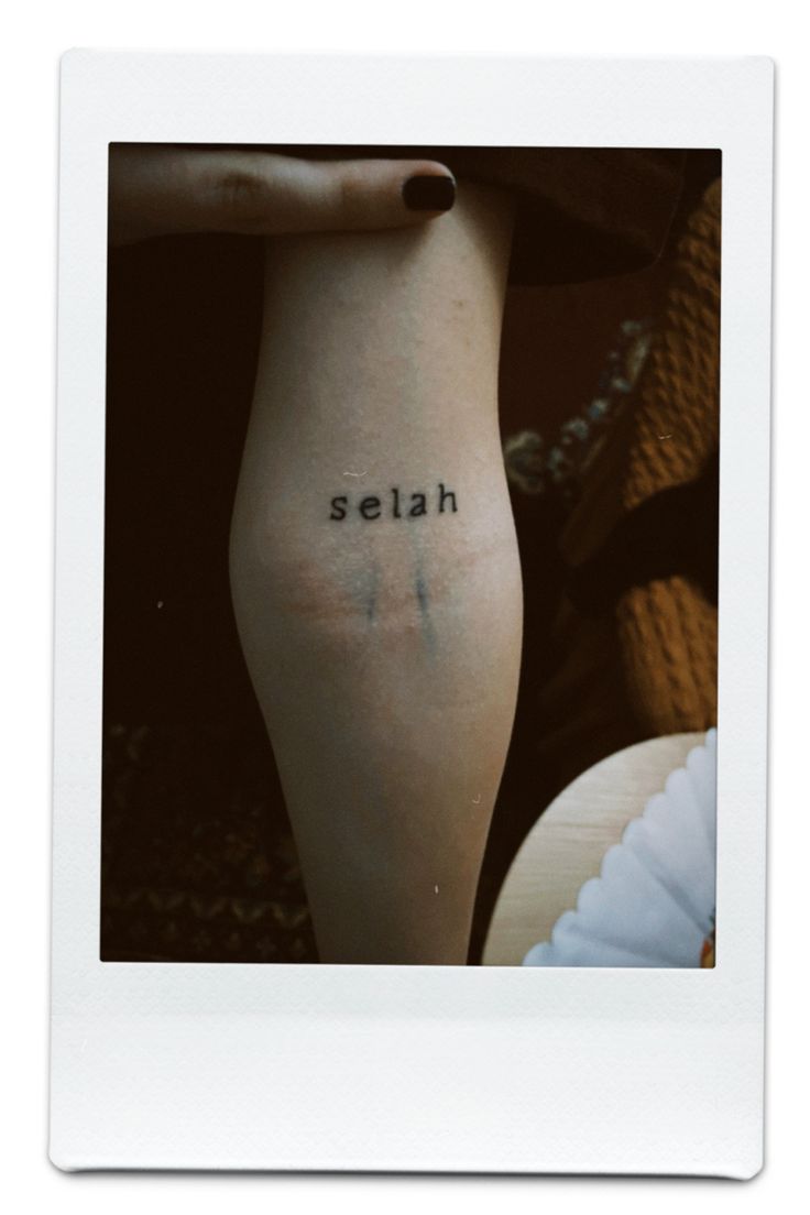 a woman's leg with the word selah tattooed on her left side