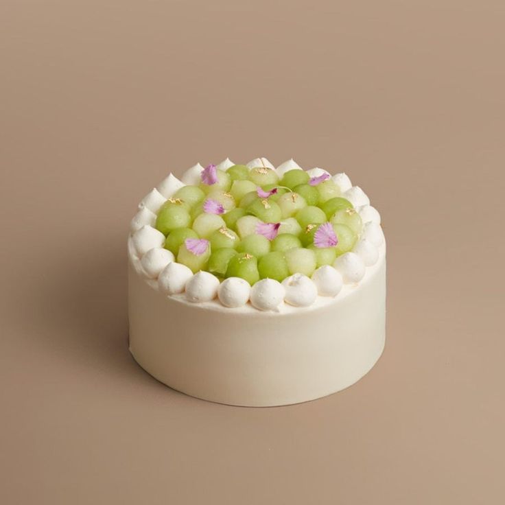 a cake with white frosting and green grapes in it on a brown table top