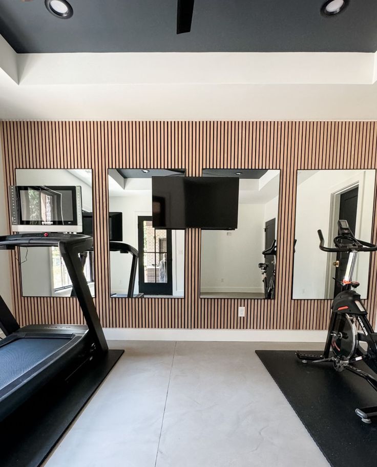 an exercise room with mirrors and treadmills on the wall in front of it