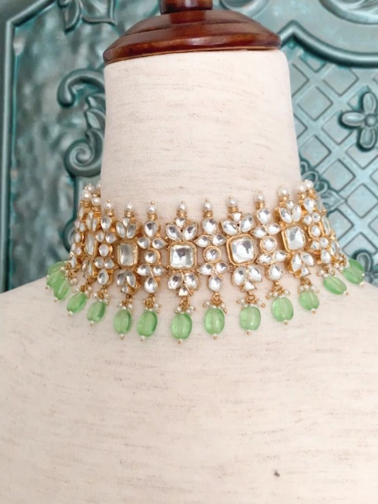 Pachi Kundan choker in white Kundan. Gold plated Kundan work.Comes with a matching pair of jhumki earring.Mint color glass bead drop detail work. Neck is about one inch and half wide and earring is about one inch in diameter . Push back. Green Kundan Necklace With Mirror Work For Festivals, Green Kundan Necklace With Mirror Work For Celebration, White Kundan Choker With Hand-set Details, Kundan Cutdana Choker Necklace, Heavy Kundan Choker Necklace, Festive Kundan Choker With Mirror Work, Kundan Choker Hand Set For Diwali, Kundan Choker Necklace For Diwali, Kundan Choker Necklace For Celebration