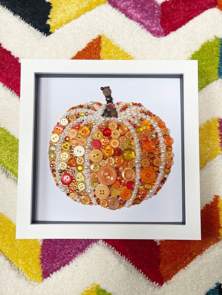 an orange buttoned pumpkin in a white frame