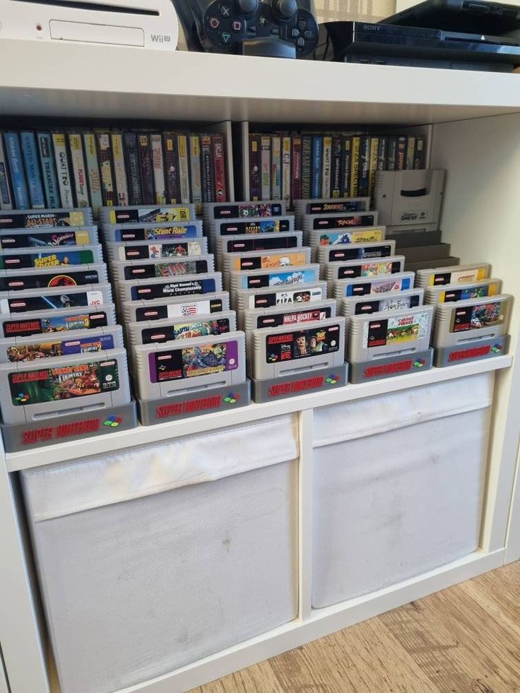 several nintendo games are stacked on top of each other in front of a white cabinet