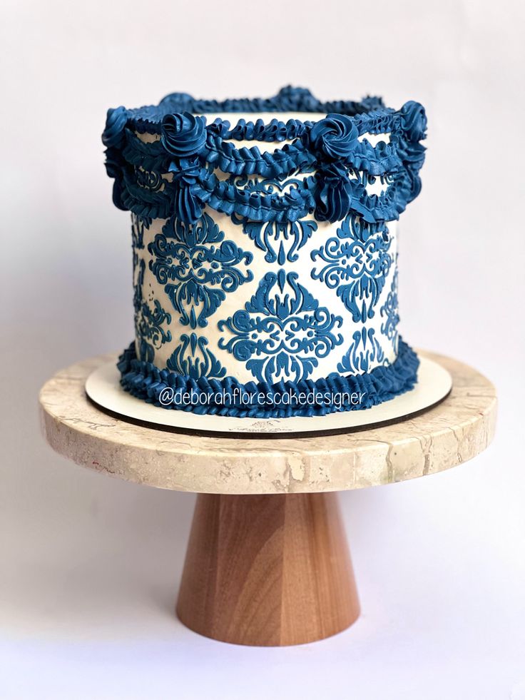 a blue and white decorated cake sitting on top of a wooden stand