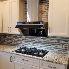 a stove top oven sitting inside of a kitchen next to white cabinets and counter tops